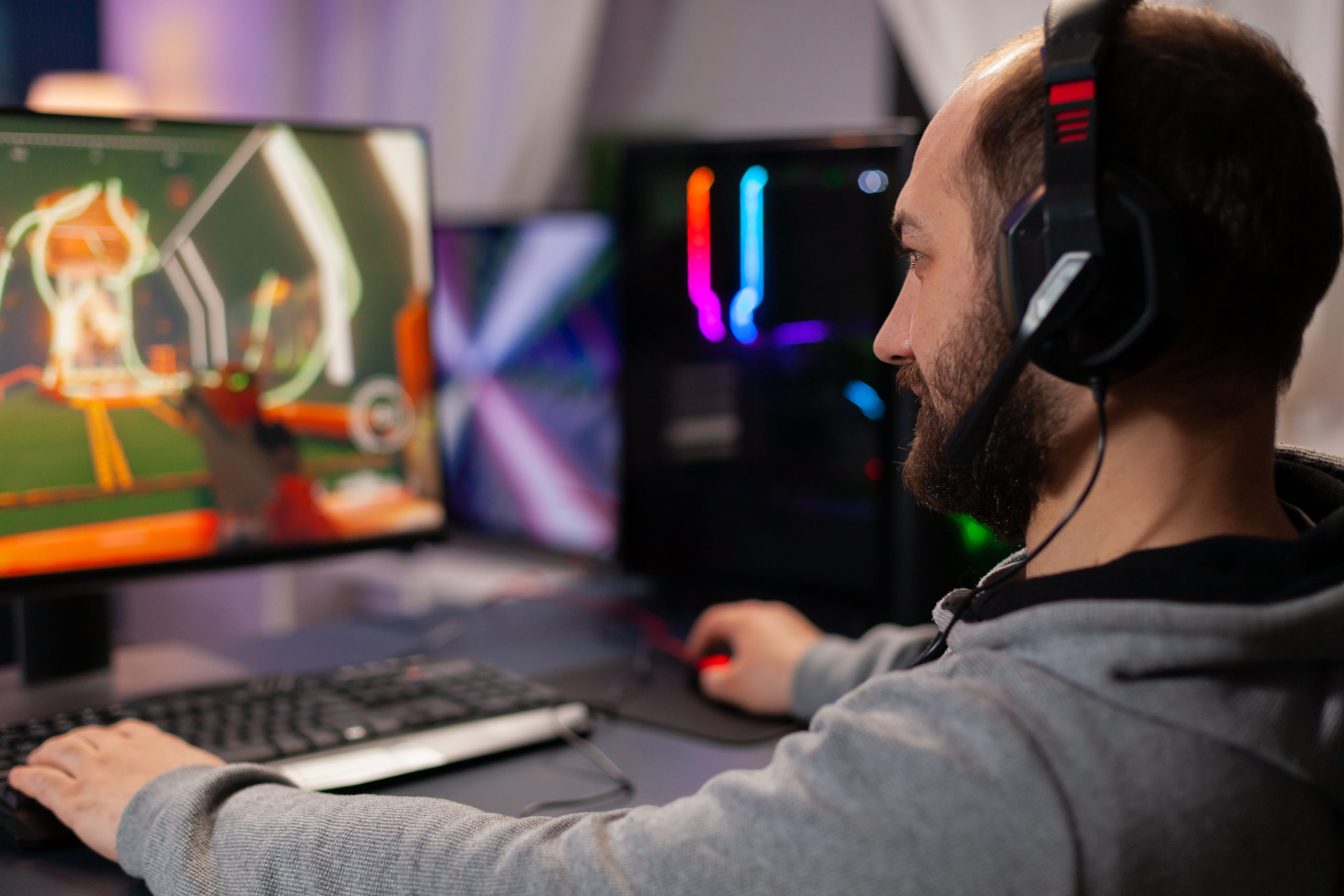 Digital player wearing headphones playing videogame with modern graphics for shooter game championship. Online streaming cyber performing during gaming tournament using powerful PC with RGB
