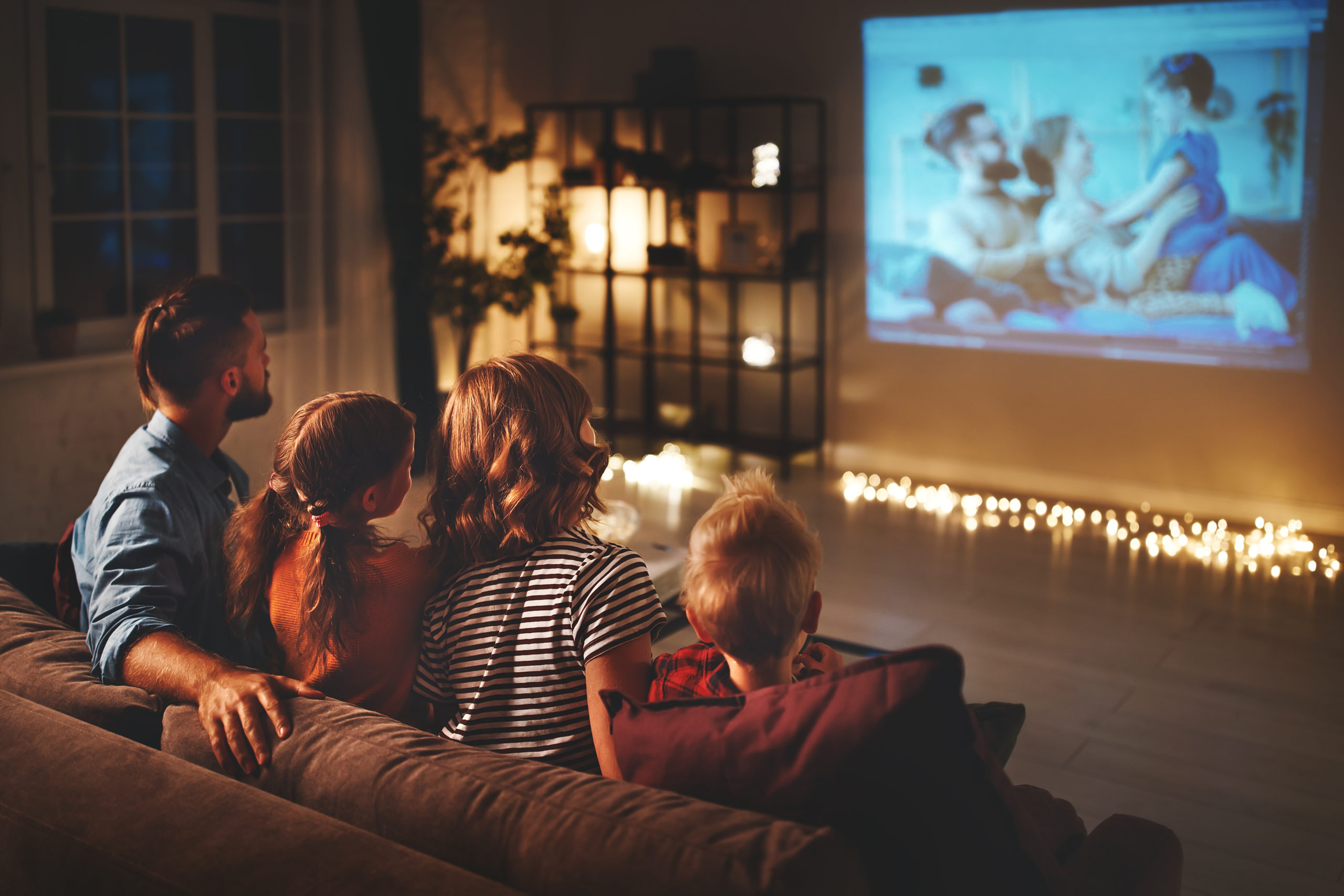 Family,Mother,Father,And,Children,Watching,Projector,,Tv,,Movies,With